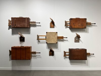 An installation showing five suitcases that are each bisected by a crutch.