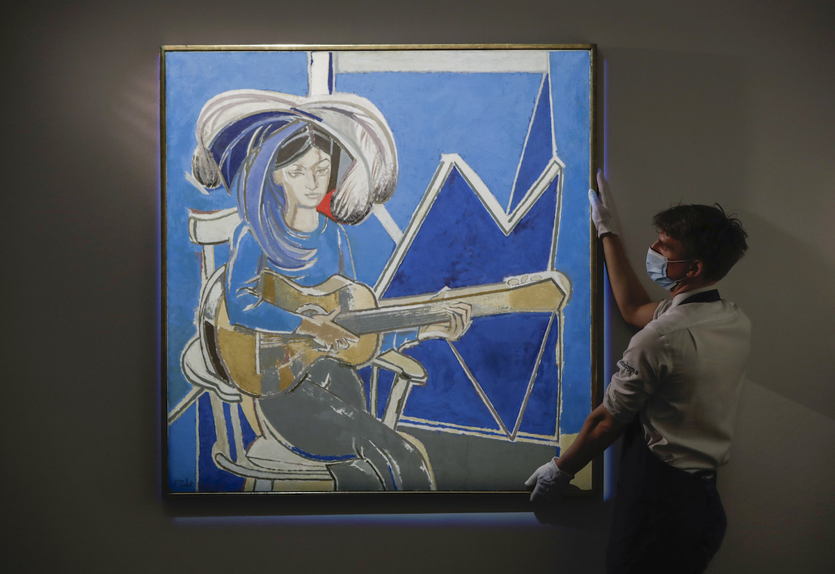 A masked person holding a painting of a woman playing guitar.