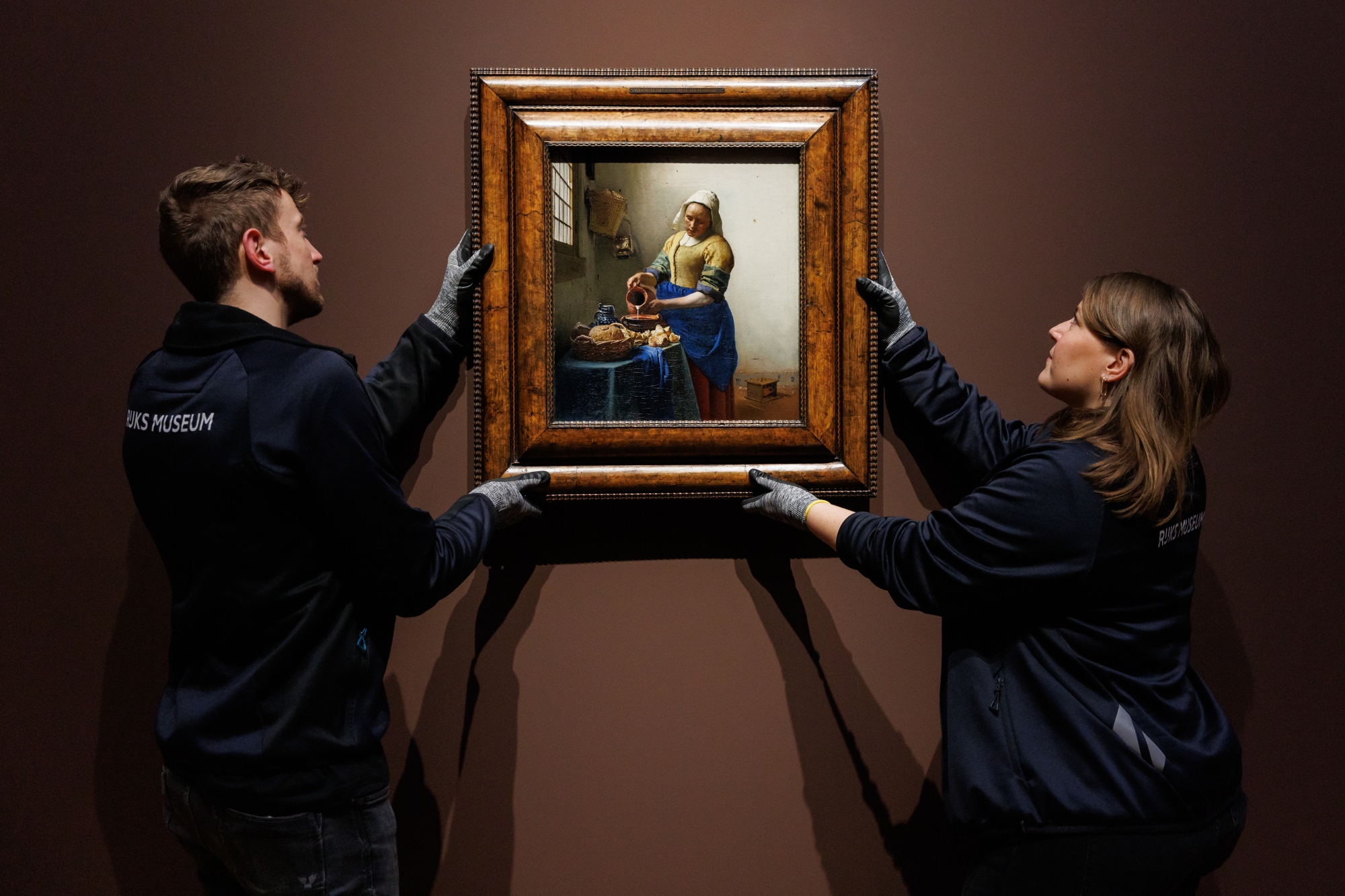 Two staff at the Rijksmuseum in Amsterdam install Johannes Vermeer's 'The Milkmaid'.
